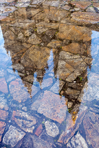 Santiago de Compostela cathedral reflection on Obradoiro town square  puddle, A Coruña province, Galicia, Spain. Water on paving stone.