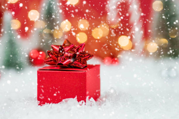 istock Banner. Christmas red gift box in a red snowy landscape on a bokeh background. Space for text. The concept of the delivery of gifts and greetings card happy New year. Close up. 1441138245