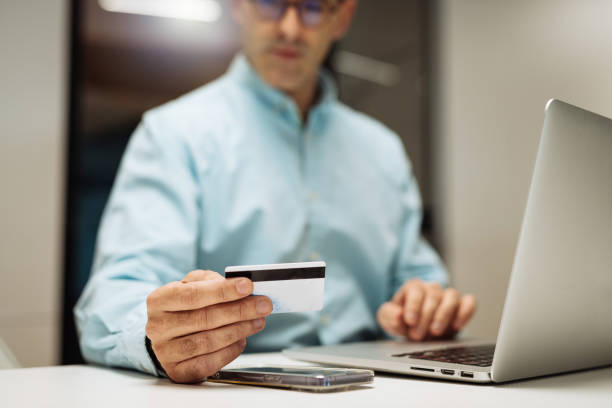 istock Mid adult businessman using laptop and credit card while using electronic banking software 1441138693