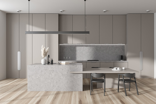 Light kitchen interior with bar island and dining table, hardwood floor. Concealed appliances design and minimalist decoration with kitchenware. 3D rendering