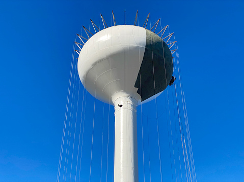 Close up of newly constructed metal water tower being painted against clear blue sky