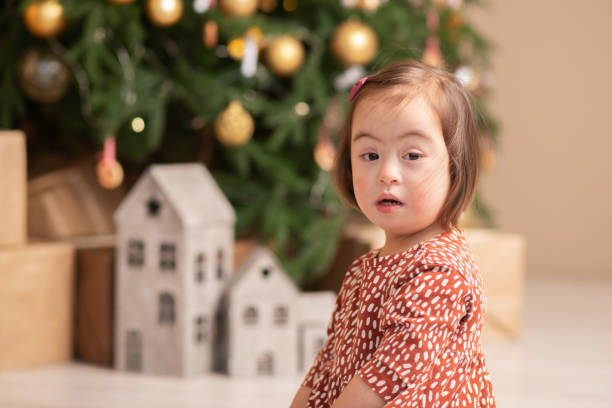 cute girl with a christmas tree with down syndrome for christmas on the background of gifts,happy new year stock photo