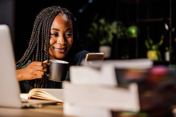istock Young woman sitting at table at the library and using smart phone during a coffee break 1441154377