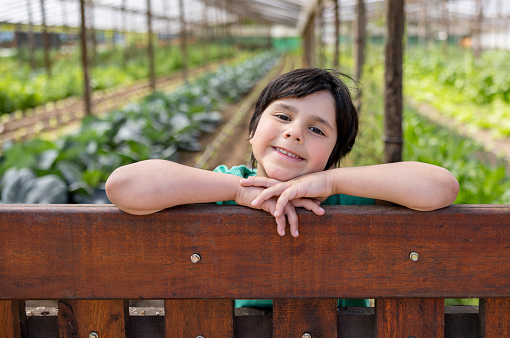 Happy Latin American boy learning about organic farming at a community garden - sustainable lifestyle concepts