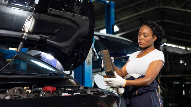istock African young female car mechanic checking and changes car air filter engine at service car garage. Black woman mechanic working in car service and maintenance workshop. 1441159574