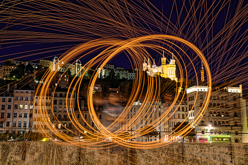 Long exposure sparks with steel wool on the quays of the Saône river in Lyon (France) in front of the Fourvière basilica and the St Georges church