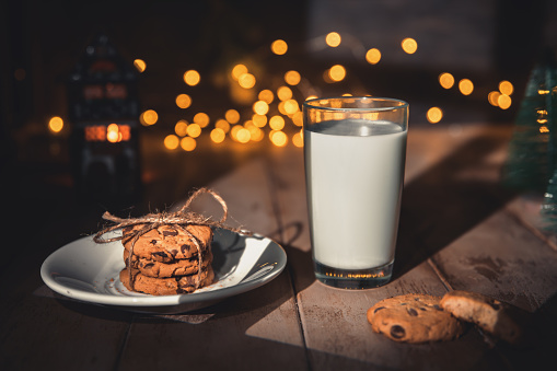 A stack of cookies and glass of milk for Santa on wooden background, concept Christmas and holiday