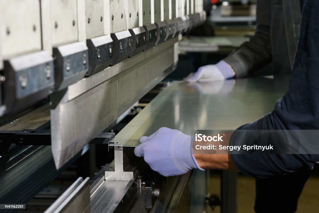 worker operating metal press machine at workshop. Car Stock Photo