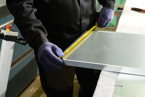 Man working in industrial metallic and use a pencil and tape measure