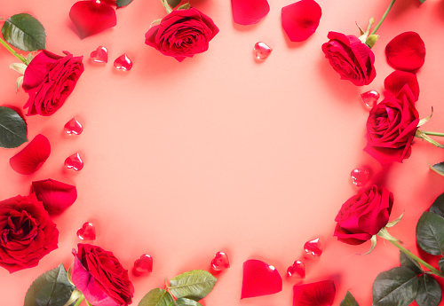 Frame of red roses and heart on pink background. Top view. Copy space. Valentines day concept