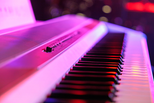 white keyboard illuminated with pink light on stage ready to play
