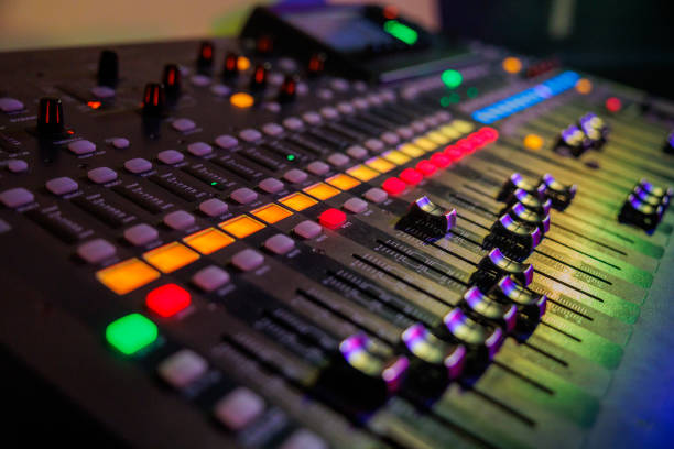 sound mixer with coloured controls and sliders illuminated by stage lights ready for music concert stock photo