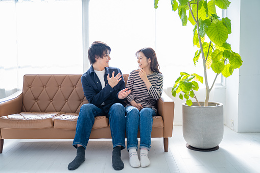 A smiling couple sitting on the sofa-living room with bright foliage plants.
