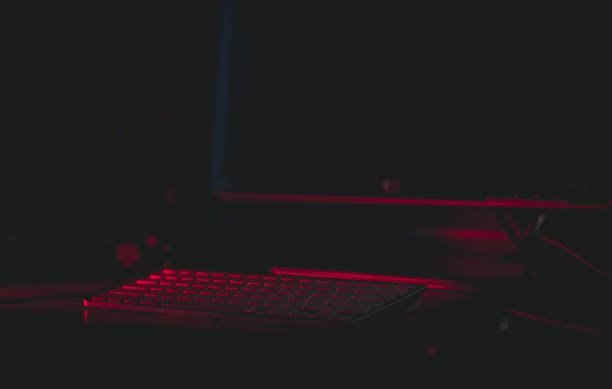 istock Closeup of a computer with red led lights on a desk against a dark blurry background 1441172132