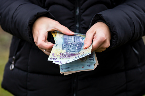 A closeup of female hands counting LEI banknotes - world money, inflation and economy concept