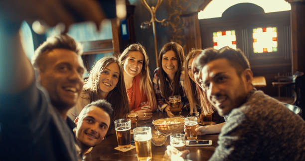 Group of friends having fun taking selfie while drinking beer in pub stock photo