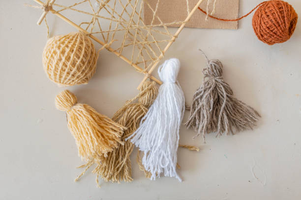 istock Work of designer, interior decoration - multi-colored tassels made of woolen thread, wooden frame lie on table. 1441173645