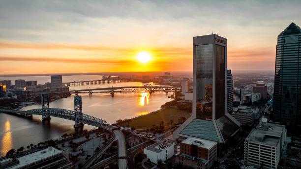 paisaje urbano con el puente acosta que cruza el río saint johns durante una puesta de sol en jacksonville - saint johns river fotografías e imágenes de stock