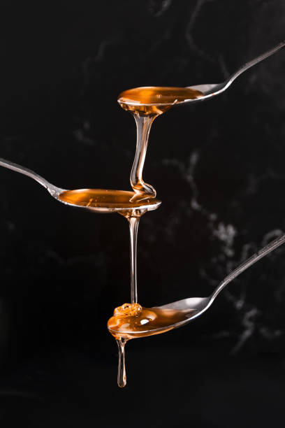 istock Spoons with pouring honey on a black background 1441174330