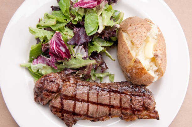 new york strip steak con insalata e patate al forno - steak strip steak prepared potato grilled foto e immagini stock