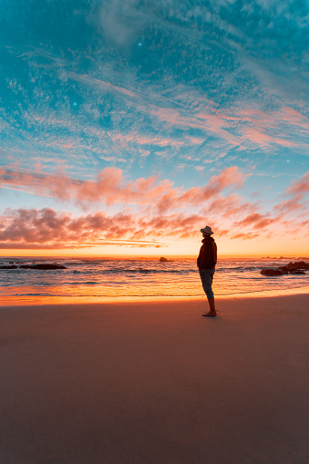 silhouette of a person on the beach contemplating a beautiful sunset on the horizon over the pacific ocean