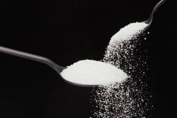istock Falling natural sugar from a small spoon into a big black spoon 1441176869