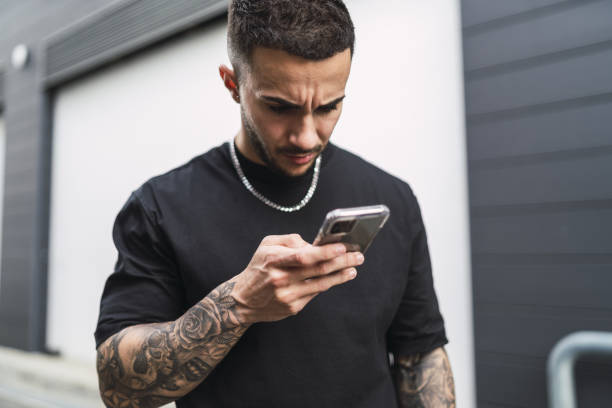 istock Spanish man with tattoos looking at his phone with a worried face 1441178314
