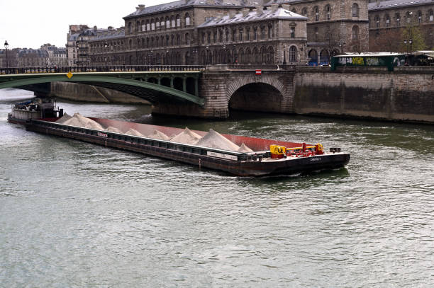 Paris, France – April 03, 2021: Bridge over the Seine river. A huge barge is passing under the brige.