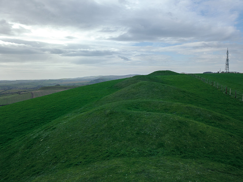 The large green burial mounds under a cloudy sky in Weymouth, Dorset, UK