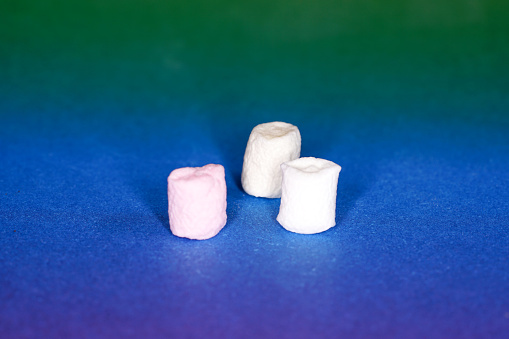 A closeup of three marshmallows on a colorful background