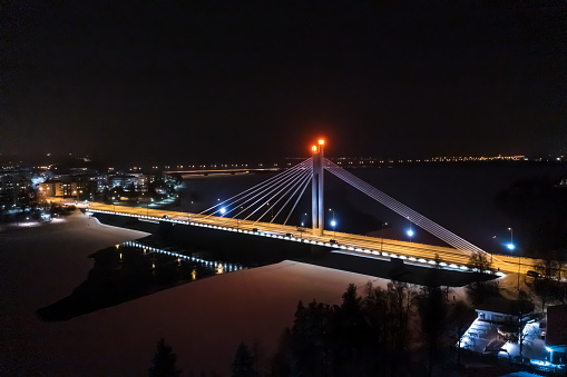 Aerial view over traffic on the Jatkankynttila bridge, in the city of Rovaniemi, winter night, in Lapland, Finland - drone shot