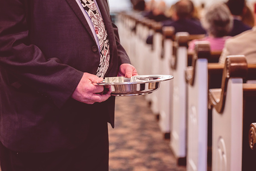 A man passing the offering plate in a traditional American church