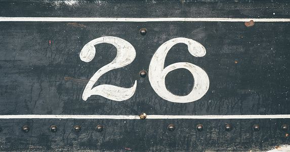 The number 26 on a dark metallic surface