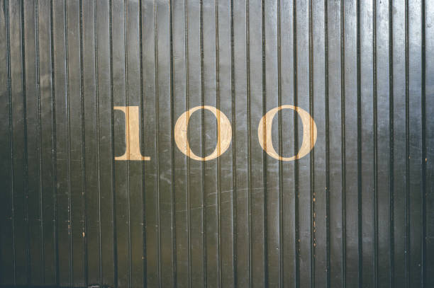 istock Number 100 written on a dark wooden gate 1441180328