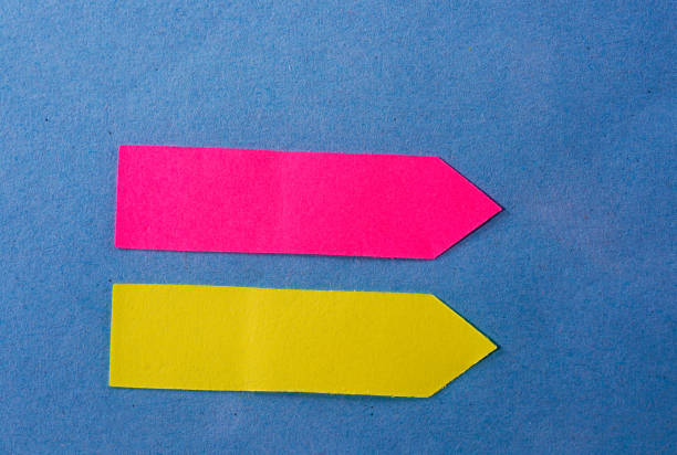 istock Closeup of pink and yellow Post-it notes on a blue paper background 1441180372