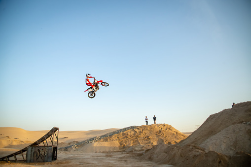 Dubai, United Arab Emirates – January 30, 2021: Freestyle motorcross riders and motorbikes in the desert jumping of dunes