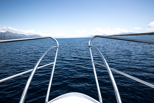 A closeup of metal handrail at the edge of the boat's deck on an ocean water background