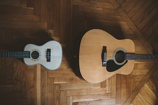 A top view of a guitar and ukulele on the wooden floor