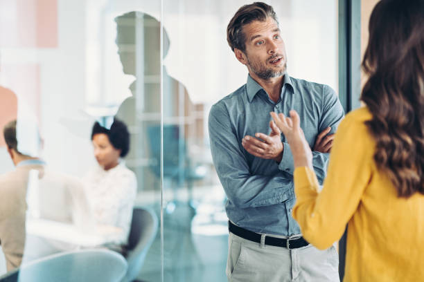 Discussion between business partners Couple of business persons standing in the office and talking arguing stock pictures, royalty-free photos & images
