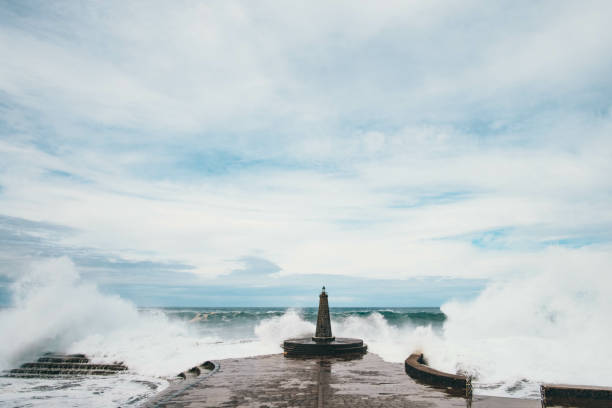 istock Big waves hitting the stone pier during a cloudy day 1441183375