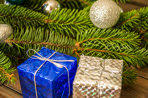 A silver shard hangs on the Christmas tree, next to the gifts. Next to the goth of gifts hangs a Christmas tree toy. toys on the Christmas tree - Christmas and New Year.