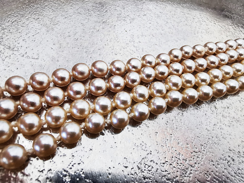 A closeup shot of beautiful pearl beads on a shiny metal surface