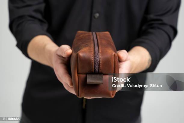Mans Brown Leather Personal Cosmetic Bag Or Pouch For Toiletry Accessory In A Mens Hands In Black Shirt Style Retro Fashion Vintage And Elegance Stock Photo - Download Image Now
