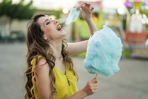 A closeup shot of a Caucasian female eating a piece of her blue cotton candy