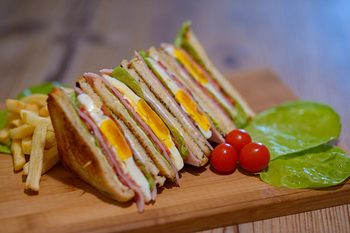 A selective focus shot of sandwiches with egg and ham on a cutting board