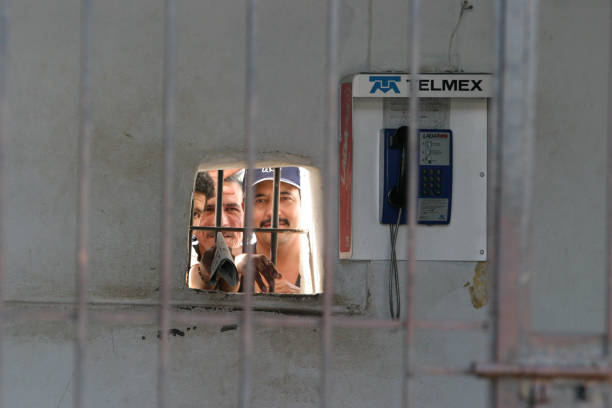 Cabo, Mexico – February 10, 2005: Inmates peaking out of a jail cell in Mexico, you can see the cell window clearly on the public street sidewalk.