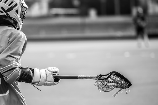 A high schhol boy lacrosse player taking a shot on goal during a game.