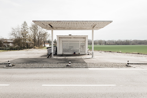 White roofing and building of a small deserted closed petrol station on a rural country road in spring in Bavaria, Germany