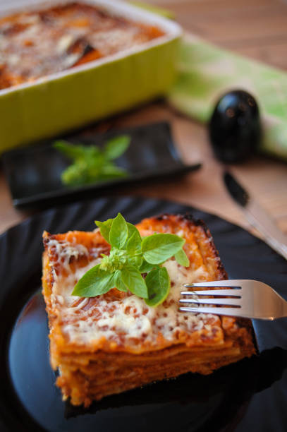 A vertical shot of a cheese lasagna served on a black plate