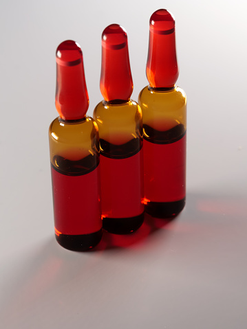 A vertical shot of three red ampoules isolated on a white background